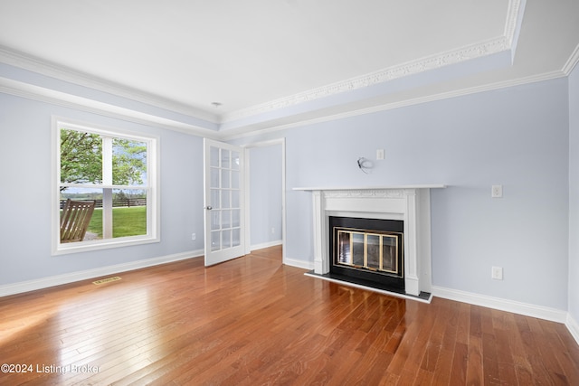 unfurnished living room featuring crown molding, wood-type flooring, and a tray ceiling