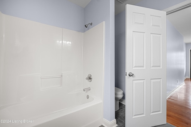 bathroom with wood-type flooring, shower / bath combination, and toilet