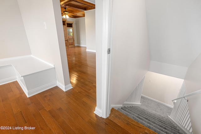 corridor featuring coffered ceiling, beam ceiling, and hardwood / wood-style floors