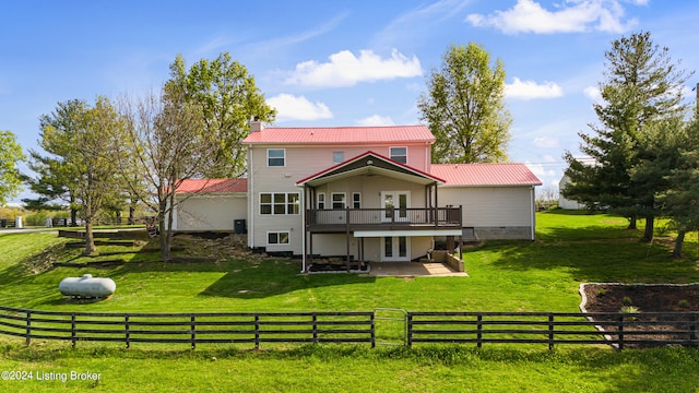 rear view of property with a deck, a rural view, and a lawn