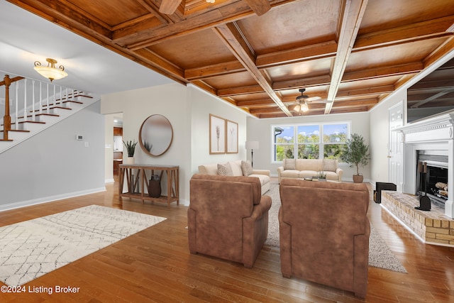 living room with hardwood / wood-style flooring, coffered ceiling, ceiling fan, and a fireplace