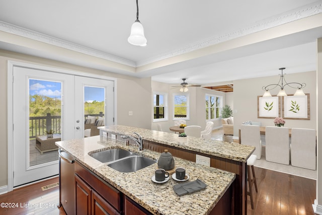 kitchen with a healthy amount of sunlight, a kitchen island with sink, and sink