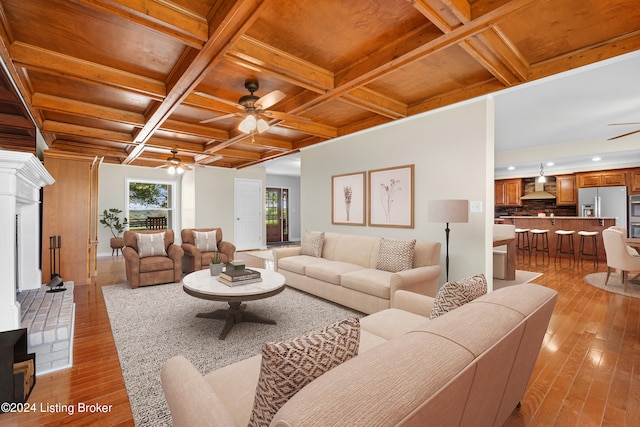 living room with beamed ceiling, light wood-type flooring, ceiling fan, and coffered ceiling