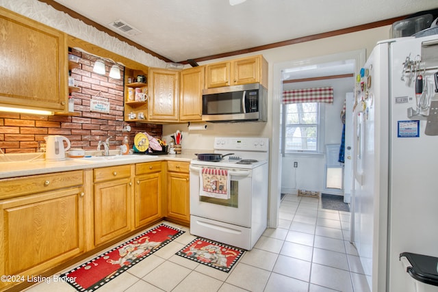 kitchen featuring a sink, light tile patterned floors, visible vents, light countertops, and white appliances