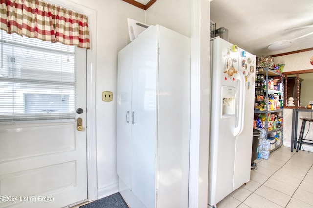 interior space featuring white refrigerator with ice dispenser and light tile patterned flooring