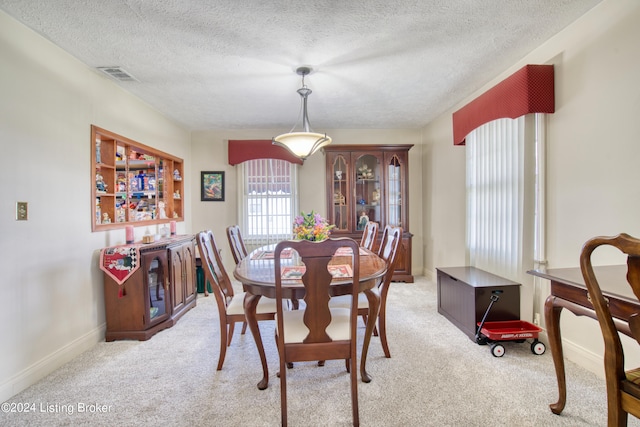 dining area featuring baseboards, visible vents, light colored carpet, and a textured ceiling