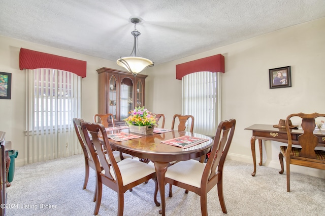 dining space with light colored carpet, baseboards, and a textured ceiling