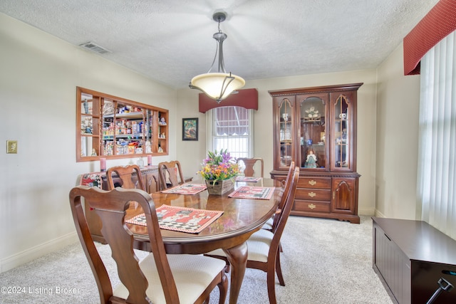 dining room featuring baseboards, visible vents, light colored carpet, and a textured ceiling