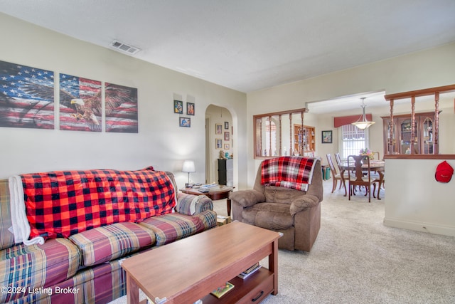 living area with baseboards, visible vents, light carpet, and arched walkways