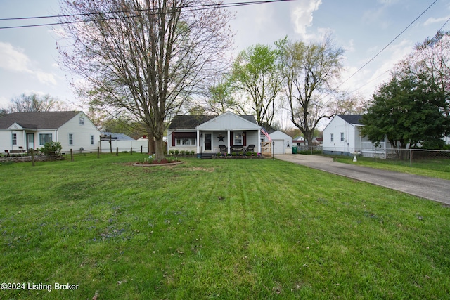 view of front of property featuring fence, a porch, a detached garage, and a front yard