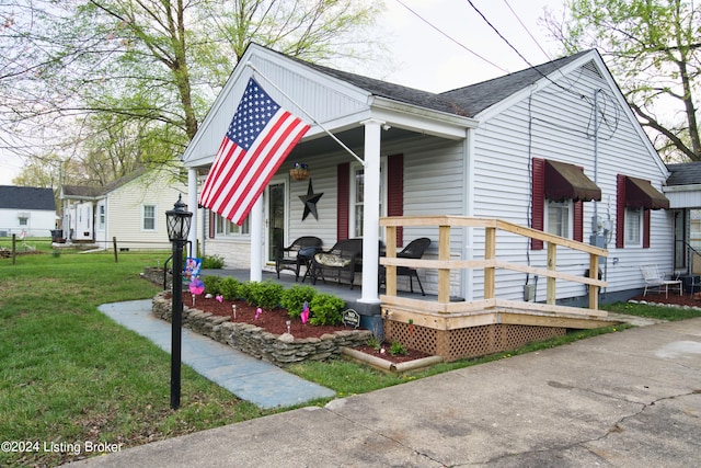 view of front of house featuring a front yard, roof with shingles, and covered porch