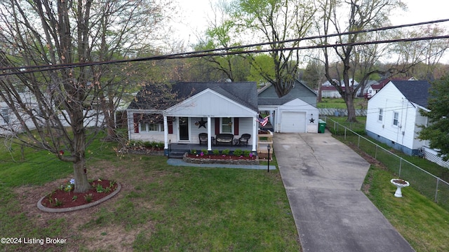 view of front of home with a front lawn, covered porch, driveway, and a detached garage