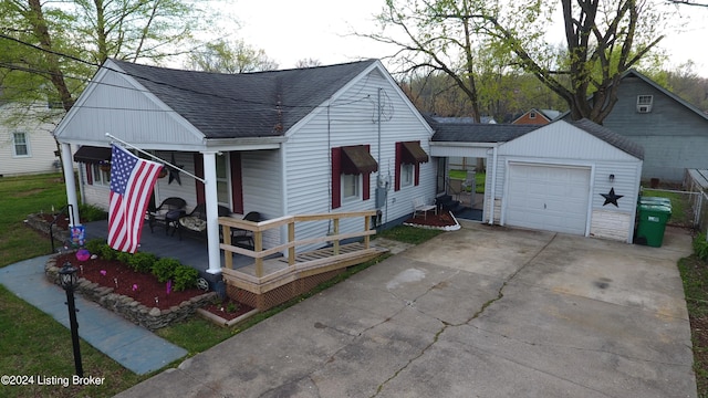 view of front of property featuring an outbuilding, roof with shingles, driveway, a garage, and a porch