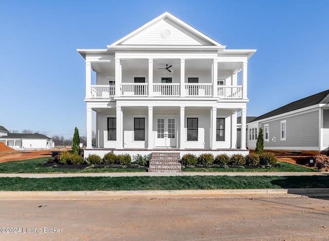 greek revival inspired property with covered porch, a balcony, and french doors