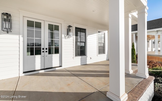 view of exterior entry featuring covered porch and french doors