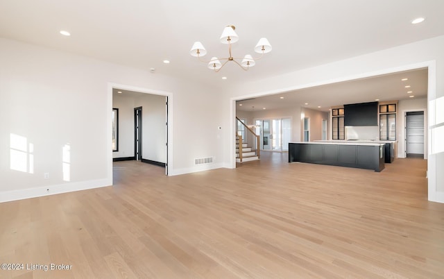 unfurnished living room with a chandelier and light hardwood / wood-style floors