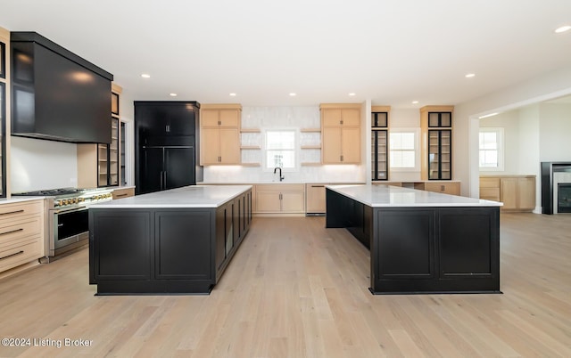 kitchen with sink, a center island, light brown cabinets, light hardwood / wood-style floors, and high end stainless steel range