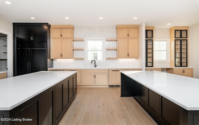 kitchen featuring light brown cabinets, a spacious island, backsplash, and light hardwood / wood-style flooring