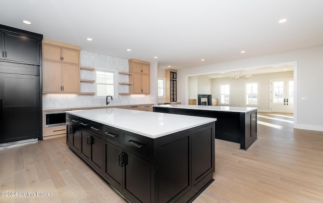 kitchen with light brown cabinets, a center island, a wealth of natural light, and paneled built in fridge