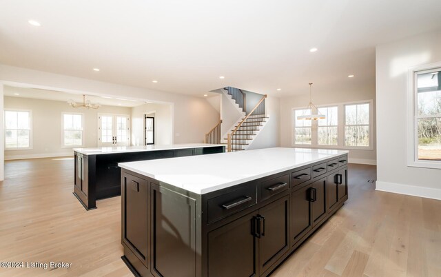 kitchen with a center island, hanging light fixtures, a notable chandelier, and light wood-type flooring