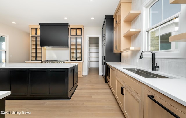 kitchen with light wood-type flooring, tasteful backsplash, extractor fan, sink, and light brown cabinets