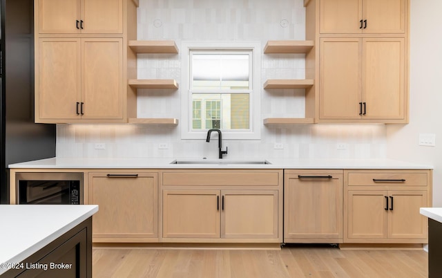 kitchen with light brown cabinets, backsplash, light hardwood / wood-style floors, and sink