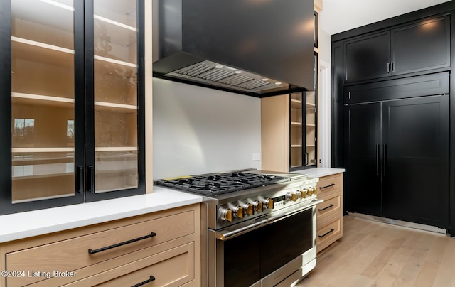 kitchen with light wood-type flooring, light brown cabinetry, premium appliances, and wall chimney range hood