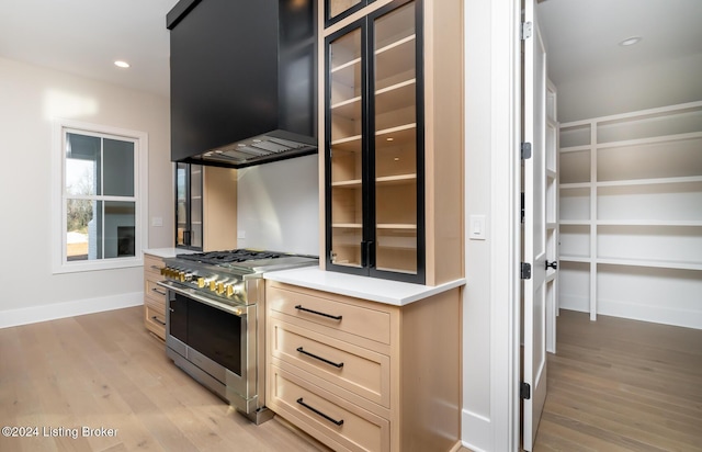 kitchen with premium range hood, light brown cabinets, double oven range, and light hardwood / wood-style flooring