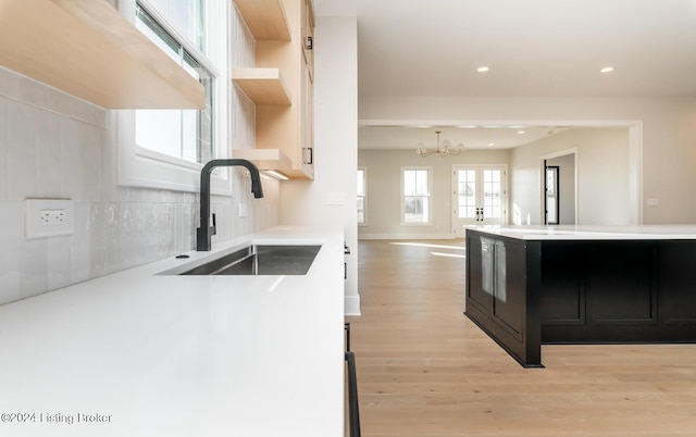 kitchen featuring a chandelier, tasteful backsplash, light hardwood / wood-style flooring, and sink