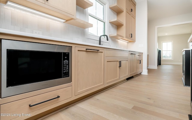 kitchen featuring stainless steel microwave, light brown cabinets, and light wood-type flooring