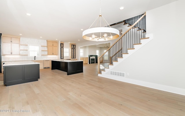 kitchen featuring light brown cabinetry, a notable chandelier, hardwood / wood-style floors, a kitchen island, and hanging light fixtures