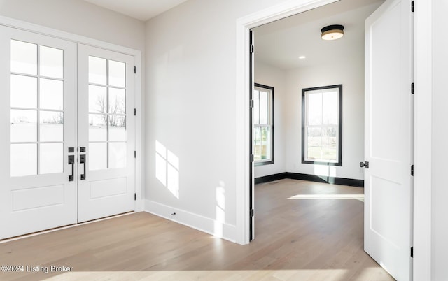 foyer entrance with french doors and light hardwood / wood-style flooring