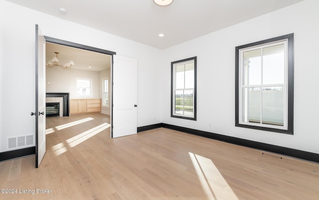 unfurnished bedroom featuring a chandelier, light hardwood / wood-style flooring, and a fireplace