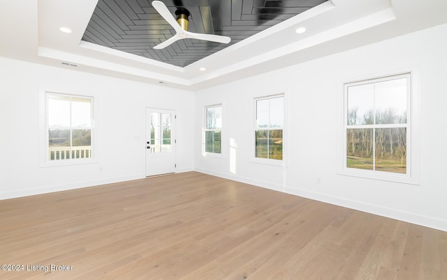 empty room featuring light hardwood / wood-style floors, a raised ceiling, and ceiling fan