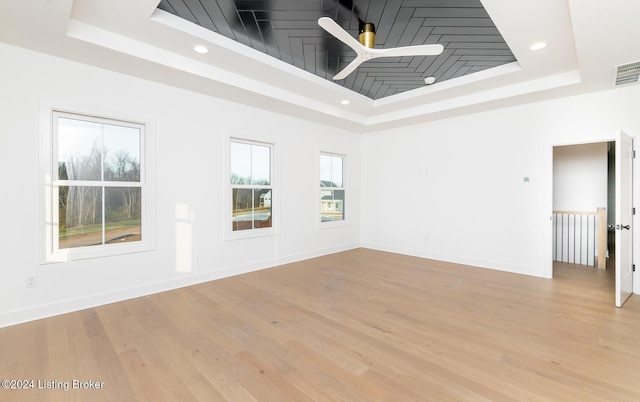 unfurnished room featuring light wood-type flooring, a raised ceiling, and ceiling fan