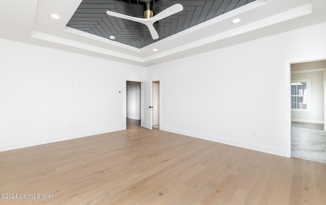 spare room with a raised ceiling, ceiling fan, and hardwood / wood-style flooring