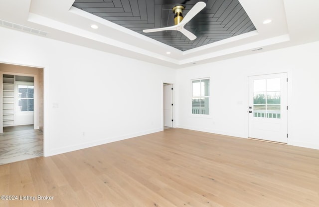 unfurnished room featuring ceiling fan, light hardwood / wood-style floors, and a raised ceiling