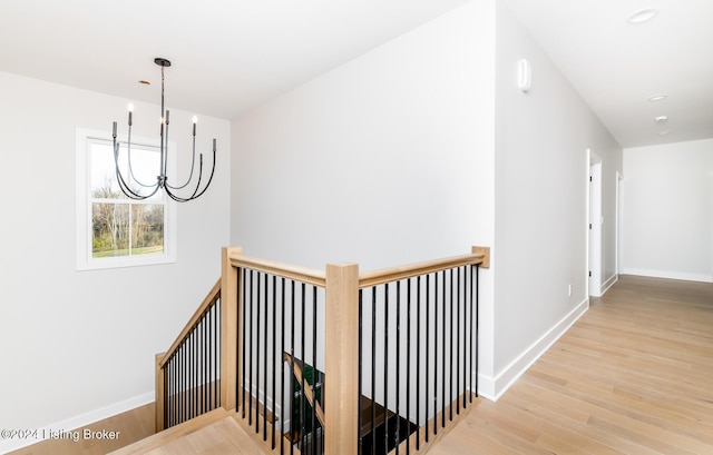 hallway with light hardwood / wood-style flooring and a notable chandelier