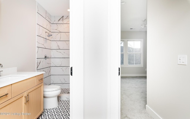 bathroom featuring ceiling fan, toilet, vanity, and tiled shower