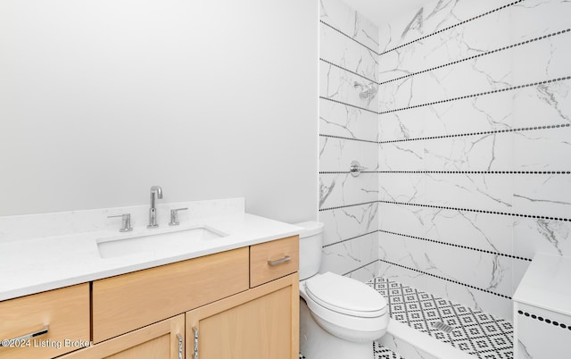 bathroom featuring vanity, toilet, and tiled shower