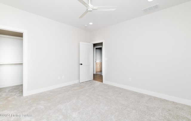 unfurnished bedroom with light carpet, a closet, a spacious closet, and ceiling fan