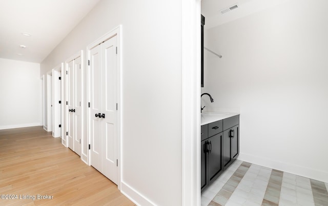 corridor with light hardwood / wood-style floors and sink