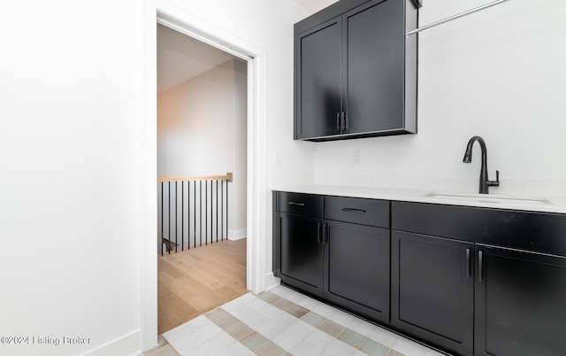 interior space with light hardwood / wood-style floors, light stone countertops, and sink