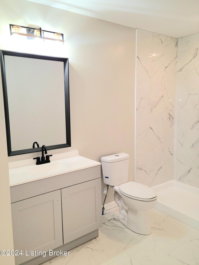 bathroom with a tile shower, vanity, and toilet