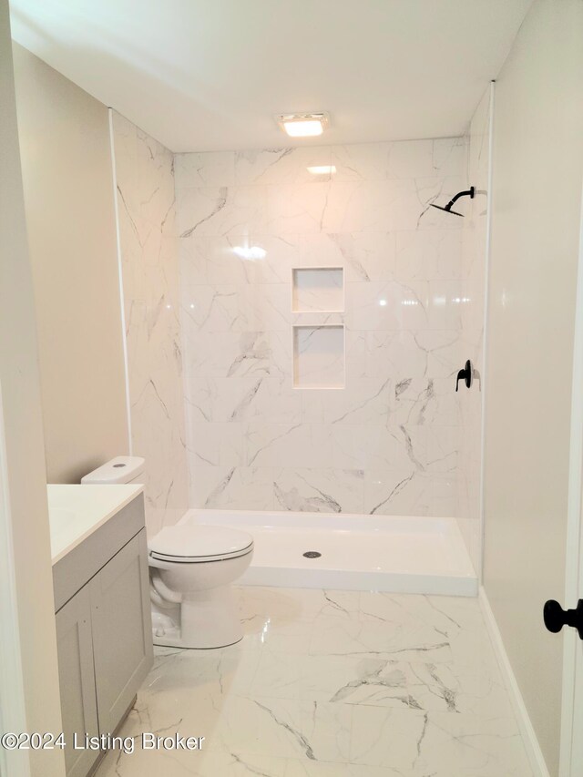 bathroom featuring tiled shower, vanity, and toilet