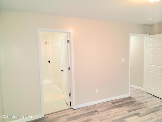 unfurnished bedroom with light wood-type flooring and ensuite bathroom