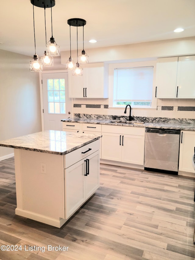 kitchen featuring light wood-type flooring, dishwasher, sink, a kitchen island, and decorative light fixtures