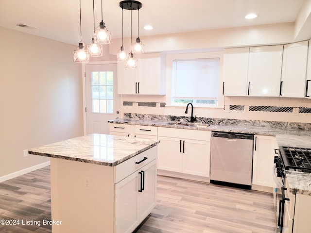 kitchen featuring stainless steel appliances, white cabinets, a center island, and sink