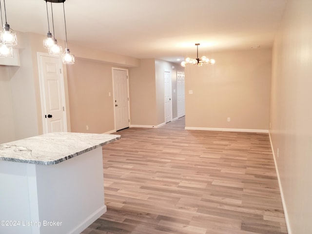 kitchen featuring light stone counters, hanging light fixtures, and light hardwood / wood-style floors