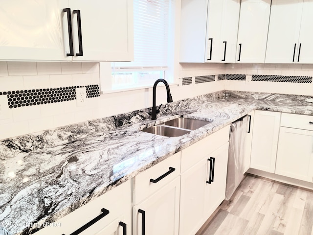 kitchen featuring white cabinets, dishwasher, light wood-type flooring, and sink